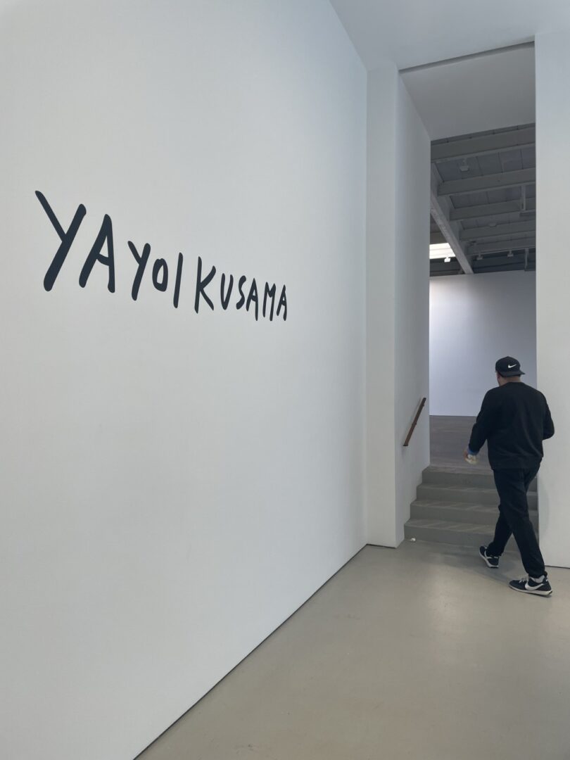 A person walking down the hall way of an art gallery.