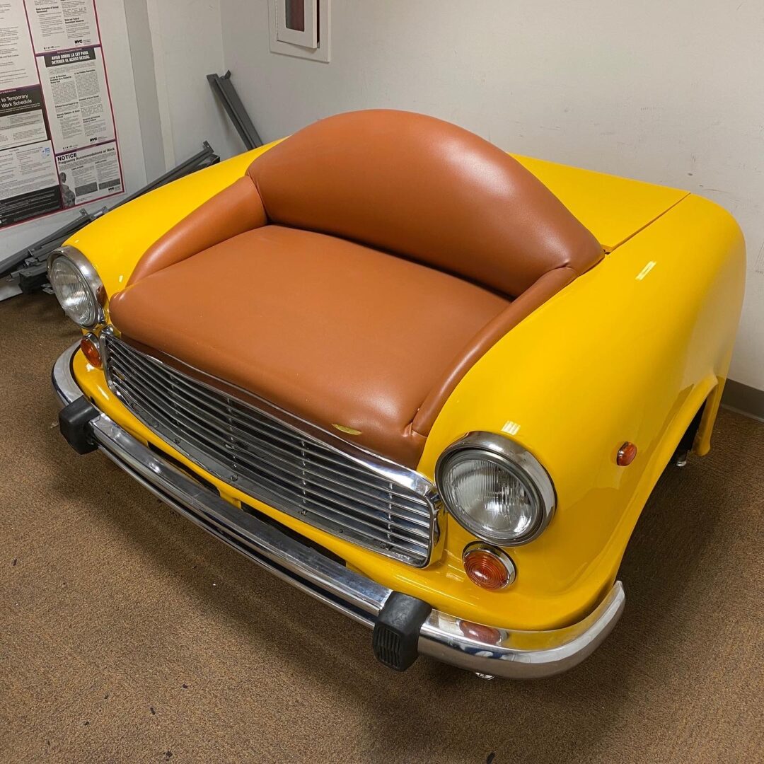 A yellow car shaped chair with brown seat.