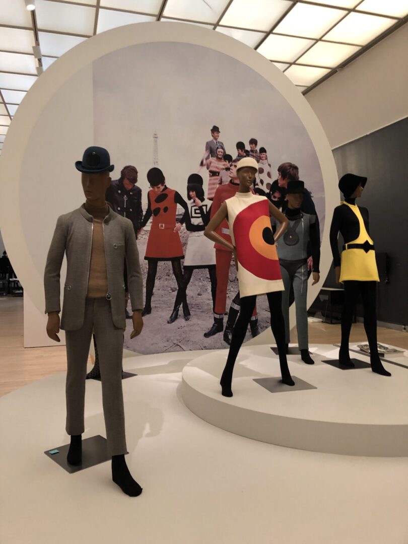 A group of mannequins in front of a round wall.
